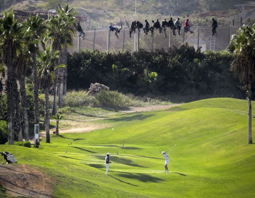 Golfeurs à Melilla jouant près de la frontière avec le Maroc, le 22 octobre 2014. A quelques mètres de la barrière où sont juchés des migrants qui tentent de passer dans l'enclave espagnole. Pour de là gagner l'Europe, en vertu des accords de Schengen. (REUTERS/Jose Palazon)