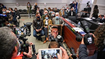 Le frère et les parents d'Arthur Noyer posent avec un portrait du caporal, à l'ouverture du procès Nordahl Lelandais, le 3 mai 2021 à Chambéry (Savoie). (PHILIPPE DESMAZES / AFP)