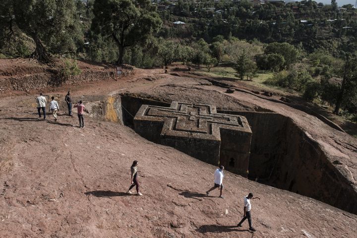 Des touristes à proximité de l'église rupestre de Saint-Georges qui fait partie des 11 églises monolithiques creusées dans la roche à Lalibela, village situé à 2600 m d'altitude, dans le nord de l'Ethiopie (photo datée du 6 mars 2019). (EDUARDO SOTERAS / AFP)