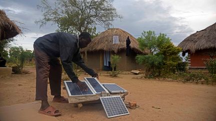 Un homme installe un kit solaire pour recharger des appareils électriques dans le village de Soroti en Ouganda.
 (ISAAC KASAMANI / AFP)