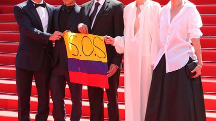 Les actrices et acteurs du film "Memoria" d'Apichatpong tiennent dans la main un drapeau colombien sur lequel il est inscrit "S.O.S" pour témoigner leur soutien à la population.&nbsp;La Colombie est en proie&nbsp;à des mouvements de colère populaire, envers le gouvernement. (MATT BARON/SHUTTERSTOCK/SIPA / SHUTTERSTOCK)