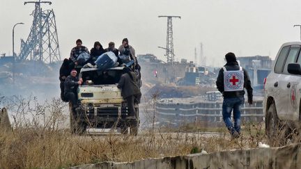 Des habitants sont évacués des quartiers rebelles d'Alep (Syrie), le 16 décembre 2016, sous le regard d'un membre du Comité international de la Croix-Rouge. (AFP)