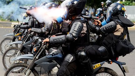 Des policiers indon&eacute;siens tirent du gaz lacrymog&egrave;ne sur des &eacute;tudiants qui manifestent contre la d&eacute;cision du gouvernement d'augmenter le prix de l'essence, Makasar (Indon&eacute;sie), le 27 mars 2012. (JALIN / AFP)