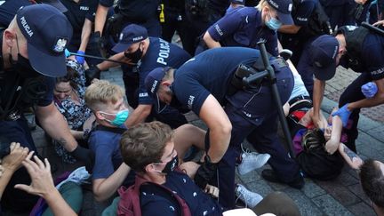 Des policiers tentent de déloger des manifestants LGBT qui s'opposent à l'arrestation d'une activite, à Varsovie en Pologne, le 7 août 2020. (JANEK SKARZYNSKI / AFP)