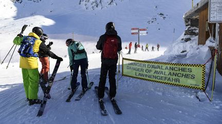 Des skieurs passent devant une banderole de vigilance pour les avalanches, le 6 janvier 2018, à Val-Thorens (Savoie). (PHILIPPE DESMAZES / AFP)