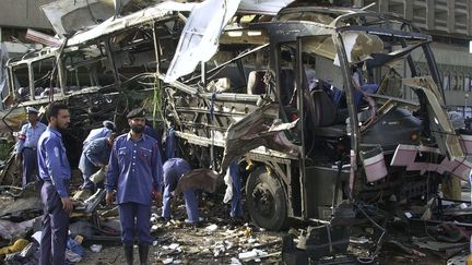 Des officiels pakistanais examinent le bus, dans lequel 11 employés français de la Direction&nbsp;des constructions navales ont perdu la vie, à Karachi le 8 mai 2002. (AAMIR QURESHI / AFP)