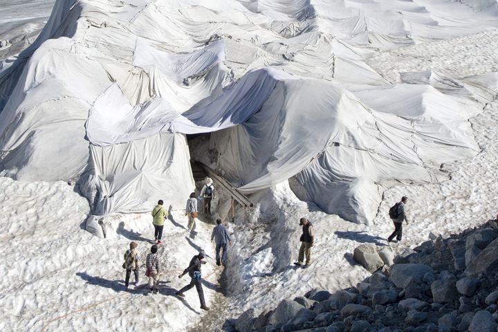 Des touristes visitent le glacier du Rhône (Suisse), protégé par des bâches blanches, le 19 juillet 2016. (MAXPPP)