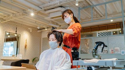 Femme sur sa tablette numérique dans un salon de coiffure. (RECEP-BG / GETTY IMAGES)