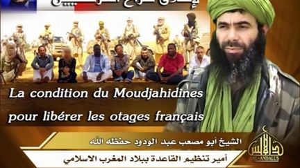 Abou Moussab Abdul Wadud, le chef d'Al-Qaïda au Maghreb islamique (AQMI), en arrière plan les otages français enlevés (AFP PHOTO/SITE/HANDOUT)