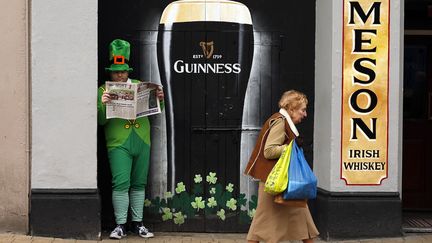 Un homme d&eacute;guis&eacute; en&nbsp;leprechaun lit le journal le jour de la Saint-Patrick &agrave; Londonderry (Royaume-Uni), le 17 mars 2015. (CATHAL MCNAUGHTON / REUTERS)