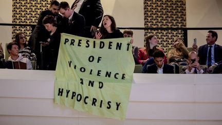 La banderole "Président de la violence et de l'hypocrisie", déployée durant le discours d'Emmanuel Macron à La Haye, le 11 avril 2023. (ROBIN VAN LONKHUIJSEN / AFP)