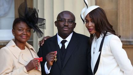 Edward Enninful, fait officier de l'ordre de l'Empire britannique en octobre 2016 pour sa contribution à la diversité dans la mode, pose entre la baronne Amos (g), elle aussi décorée, et sa grande amie, le mannequin Naomi Campbell. (Philip Toscano / POOL / AFP)