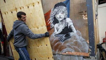 Un ouvrier recouvre une œuvre de Banksy, à Londres, lundi 25 janvier 2016. (TOLGA AKMEN / ANADOLU AGENCY / AFP)