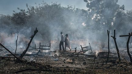 Après le bombardement du village de Kauda, un couple marche dans les cendres de sa maison. L’attaque a détruit quatre habitations de la localité, ainsi que toutes les récoltes qui venaient d’être faites. Les familles ne pourront plus assurer leur subsistance jusqu’à la prochaine moisson, en septembre de l’année suivante.  (Camille Lepage)