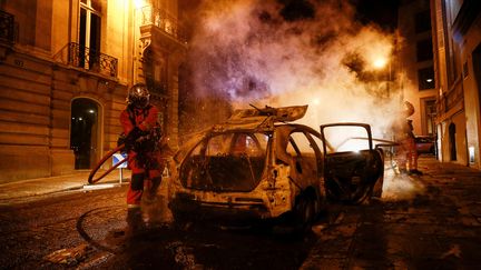 Un pompier tente d'éteindre une voiture incendiée sur les Champs-Élysées à Paris après la défaite du PSG en Ligue des champions, le 23 août 2020. (SAMEER AL-DOUMY / AFP)