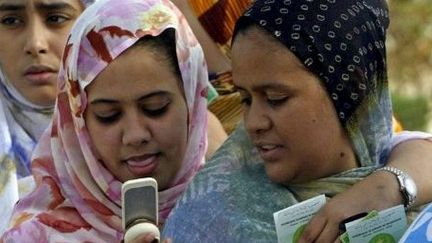 2006 en Mauritanie : des femmes attendent pour voter, tout en consultant leur téléphone portable. (AFP/SEYLLOU)