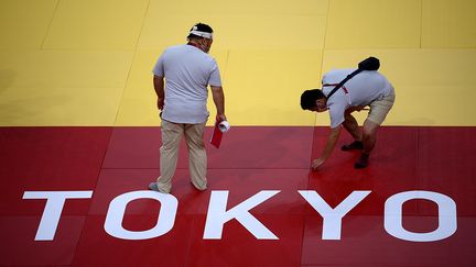 Des juges vérifient le tatami, le 21 juillet 2021, à Tokyo (Japon). (FRANCK FIFE / AFP)