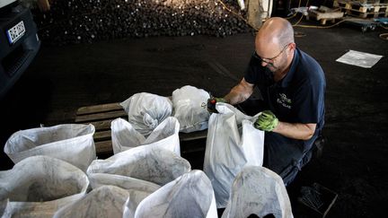 Un travailleur en train de remplir des sacs de charbon, au sein de l'entreprise familiale centenaire "Hans Engelke Energie", à Berlin&nbsp; (CARSTEN KOALL / AFP)