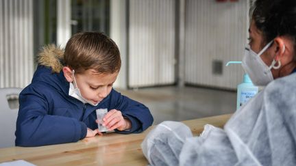 Un élève en école élémentaire effectue un test salivaire Covid-19 en crachant dans un tube à essai, à l'école primaire de La Foret à Eysines (Nouvelle-Aquitaine), le 25 février 2021. (UGO AMEZ/SIPA)