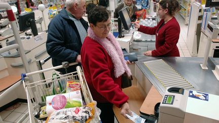 Une cliente paie en liquide à une caisse d'un supermarché, en décembre 2007. (FRANK PERRY / AFP)