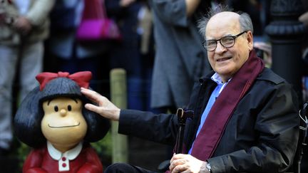 Le caricaturiste Quino pose à côté d'une sculpture de Mafalda à Oviedo, en Espagne, le 23 octobre 2014. (MIGUEL RIOPA / AFP)