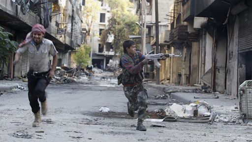 A droite, Mohamed, 13 ans, qui se bat dans les rangs du mouvement Armée syrienne libre (soutenue par les Occidentaux), tente d'échapper à des snipers à Alep (Syrie) le 29 octobre 2013. Il a rejoint les rangs de ce mouvement après la mort de son père au cours de combats avec l'armée du régime. (Reuters - Molhem Barakat)