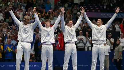 Yohann Ndoye-Brouard, Léon Marchand, Maxime Grousset et Florent Manaudou sur le podium du relais 4x100 m 4 nages, aux Jeux olympiques de paris 2024, à Paris La Défense Arena, à Nanterre, le 4 août 2024. (OLI SCARFF / AFP)