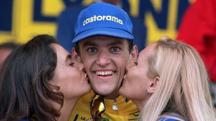 Jacky Durand, maillot jaune surprise du Tour 1995, est embrassé par les hôtesses sur le podium du prologue de Saint-Brieuc (Côtes d'Armor), le 2 juillet. (PASCAL PAVANI / AFP)