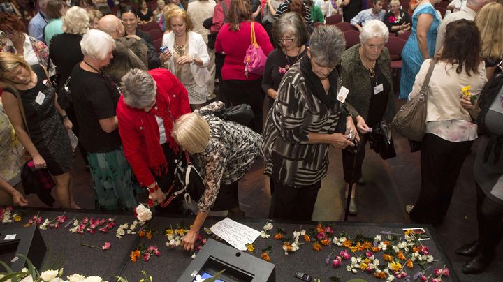 Des femmes, victimes des abandons forc&eacute;s dans les ann&eacute;es 50-70 en Australie, d&eacute;posent des fleurs sur une estrade apr&egrave;s les excuses nationales de l'Etat, le 21 mars 2013 &agrave; Canberra (Australie). (ANDREW TAYLOR / AP / SIPA )