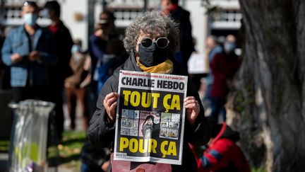 Une femme avec un exemplaire de l'hebdomadaire satirique "Charlie Hebdo", lors d'un rassemblement à Nantes,&nbsp;en hommage à Samuel Paty, le 18 octobre 2020. (ESTELLE RUIZ / HANS LUCAS / AFP)