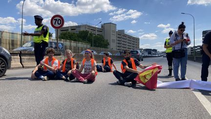 Les militants de Dernière Rénovation assis sur la chaussée au beau milieu du périphérique parisien, avant d'être délogés par les forces de l'ordre, le 9 juillet 2022. (MATHILDE GRACIA / FRANCEINFO)