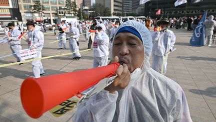 Le lendemain, ces travailleurs sud-coréens ont revêtu des combinaisons de protection pour manifester pour l'amélioration des conditions de travail à Séoul. (JUNG YEON-JE / AFP)