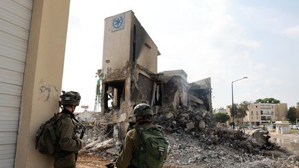 Des soldats se tiennent devant un poste de police israélien, à Sderot, endommagé lors des combats visant à déloger les militants du Hamas qui y étaient stationnés, le 8 octobre 2023. (JACK GUEZ / AFP)