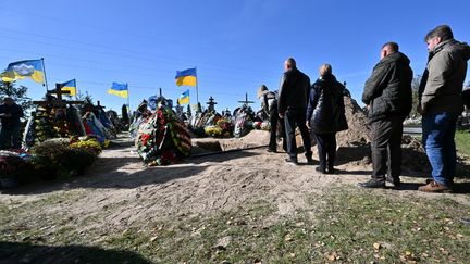 Des Ukrainiens&nbsp;font la queue en attendant de jeter de la terre sur le cercueil d'Oleksiy Telyzhenko, 44 ans, lors de sa cérémonie funéraire à&nbsp;Boutcha&nbsp;(Ukraine), le 18 octobre 2022. (SERGEI SUPINSKY / AFP)