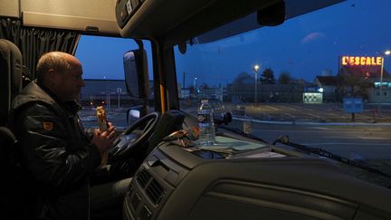 Un chauffeur routier mange dans sa cabine sur le parking du&nbsp;relais routier L'Escale, fermé pendant le confinement, le 26 mars 2020 à Deols (Indre). (GUILLAUME SOUVANT / AFP)