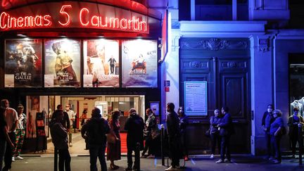 Des gens patientent devant le cinéma les 5 Caumartins, à Paris, avant la séance nocturne de réouverture de l'établissement dans la nuit du 21 au 22 juin 2020. (ABDULMONAM EASSA / AFP)