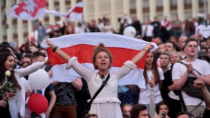 Une manifestante brandit l'ancien drapeau de la Biélorussie indépendante lors d'une manifestation contre le président Alexandre Loukachenko à Minsk, le 14 août 2020. (SERGEI GAPON / AFP)