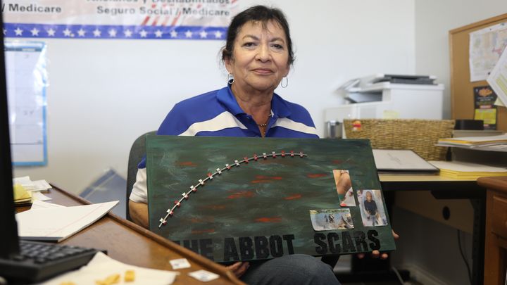 Juanita V. Martinez, présidente du Parti démocrate du comté de Maverick, porte une pancarte dénonçant les "cicatrices de Greg Abbott", le gouverneur du Texas, dues au fil barbelé posé le long du Rio Grande, le 7 mars 2024. (ELISE LAMBERT / FRANCEINFO)