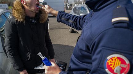 Un policier contrôle un automobiliste au stupéfiant dans le cadre d'une opération de sensibilisation des agents de la police nationale, au péage de Toulouse Nord, le 24 février 2023. (FREDERIC SCHEIBER / HANS LUCAS)