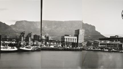 En 2001, Jean Brundrit installe un « container-appareil-photo » (sténopé) sur le front de mer du Cap qui offre une vue sur la Montagne de la Table, sur la ville et le port, ce décor qui est reproduit à l’envi sur les cartes postales du Cap. Les visiteurs sont invités à entrer dans le container. Habitués à l’obscurité, ils perçoivent une image du Cap mais à l’envers. Cette vue se reflète sur toutes les faces intérieures du container, les couvrant de couleurs et de lumières.
 (Jean Brundrit)