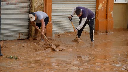 Près de Valence, des sinistrés déblaient des rues, qui ont pris la couleur de la boue après le passage des inondations. (ALEX JUAREZ / ANADOLU / AFP)