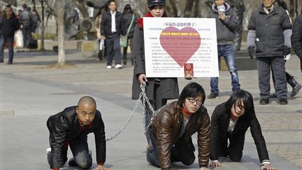 Une jeune femme chinoise tient trois hommes en laisse dans le cadre d'une performance artistique visant &agrave; d&eacute;noncer les in&eacute;galit&eacute;s entre les sexes, le 8 f&eacute;vrier 2012, &agrave; Wuhan (Chine), le 8 f&eacute;vrier 2012.&nbsp; (REUTERS )