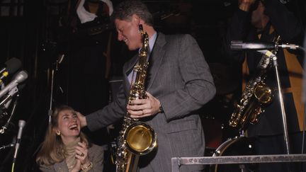 Bill Clinton, alors candidat à la présidentielle américaine, jouant du saxophone devant Hillary, en 1992. (LEE CORKRAN / SYGMA)