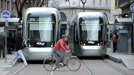 Un cycliste traverse les voies du tram à Grenoble. (PHILIPPE DESMAZES / AFP)