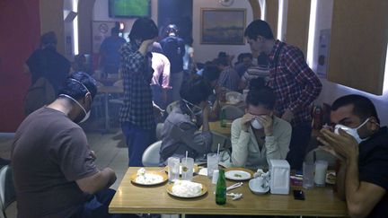 Des clients d'un restaurant situ&eacute; pr&egrave;s de la place Taksim enfilent des masques pour se prot&eacute;ger contre les gaz lacrymog&egrave;nes qui p&eacute;n&egrave;trent dans l'&eacute;tablissement &agrave; Istanbul (Turquie), le 22 juin 2013. (MARKO DJURICA / REUTERS)