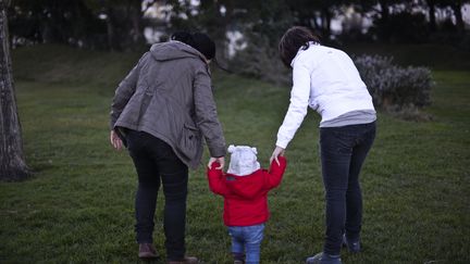 Un couple de femmes prenant un enfant par la main au Portugal dans un parc, en 2014. (PATRICIA DE MELO MOREIRA / AFP)