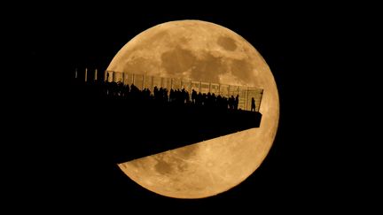 La dernière "super Lune" de l'année 2024 s'élève derrière les visiteurs de The Edge, un observatoire de New York (Etats-Unis) qui offre une vue sensationnelle sur la ville, le 15 novembre 2024. (GARY HERSHORN / CORBIS NEWS / GETTY IMAGES)