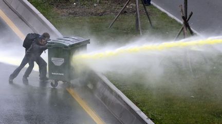 Des manifestants se prot&egrave;gent des canons &agrave; eau de la police avec une benne &agrave; ordures lors d'affrontements &agrave; Ankara (Turquie), le 11 mars 2014. (UMIT BEKTAS / REUTERS)