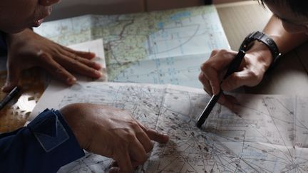 Un garde-c&ocirc;tes japonais &eacute;tudie une carte dans un avion de recherche du vol MH370, le 15 mars 2014.&nbsp; (EDGAR SU / REUTERS)