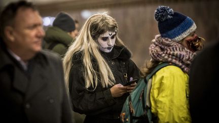 Une femme maquillée pour Halloween regarde son téléphone portable alors qu'elle attend le métro à Moscou, le 31 octobre 2018 (MLADEN ANTONOV / AFP)